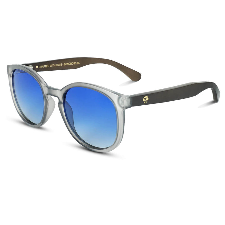 anteojos redondos de plástico reciclado y varillas de madera natural sustentable con lentes de color degrade azul. Polarizadas y forma redonda. La gafa es color transparente #color_degrade-azul