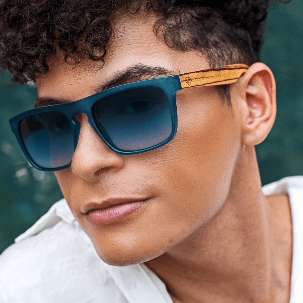 una vista frontal de anteojos gafas de sol rectangulares ecologicas de plastico reciclado especial para regalo corporativo personalizado de color azul ocean con lentes degrade azules en vista angulada en un modelo hombre #color-marco_ocean