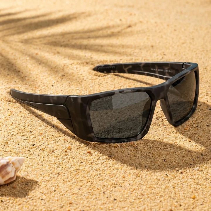 Lentes sol Salmon Seeker polarizados UV400 sobre arena dorada costa textura natural Bonoboss #color_dark-camo