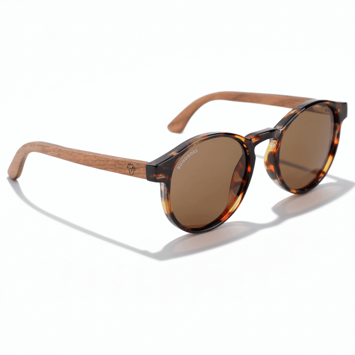 vista lateral de unos anteojos gafas de sol polarizadas de forma redonda y con puente para narices anchas hechas de plastico reciclado sustentable ecologico personalizada y patas de madera de #color_carey