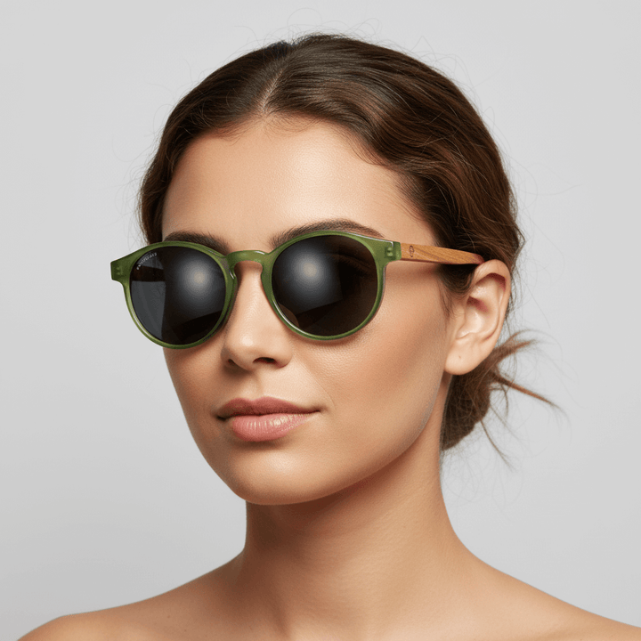vista lateral de una modelo mujer de cara redonda usando unos anteojos anteojos gafas de sol polarizadas de forma redonda y con puente para narices anchas hechas de plastico reciclado sustentable ecologico personalizada y patas de madera de #color_verde