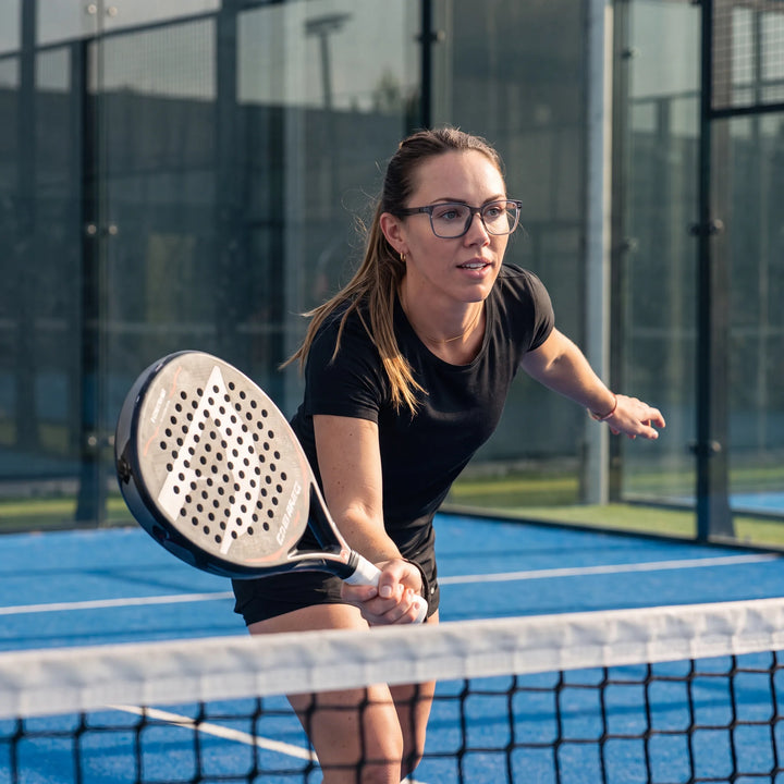 Lentes ópticos deportivos Bonoboss Comaneci Transparente, mujer practicando pádel al aire libre con el armazón puesto #editorial_modelo6 #color_transparente