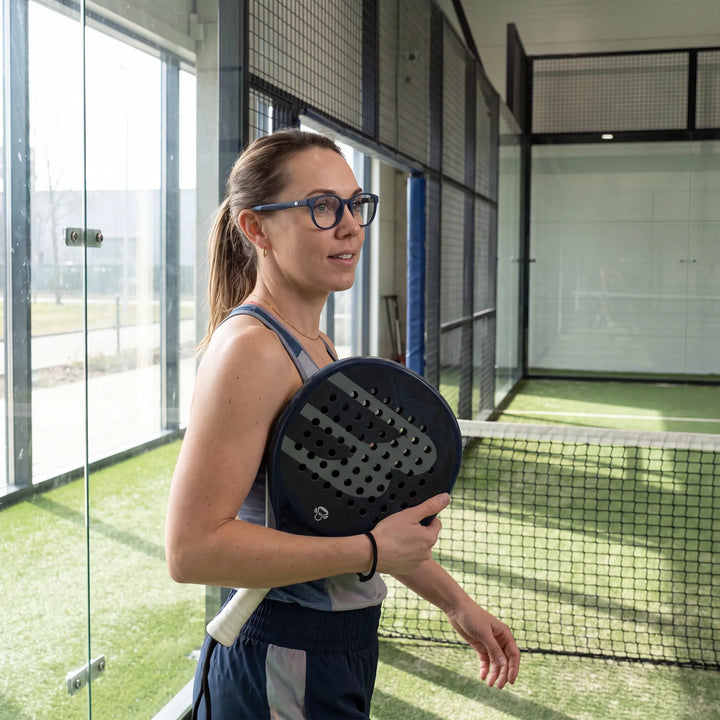 Lentes ópticos deportivos Bonoboss Simone Azul, mujer practicando pádel al aire libre con el armazón puesto #editorial_modelo6 #color_azul