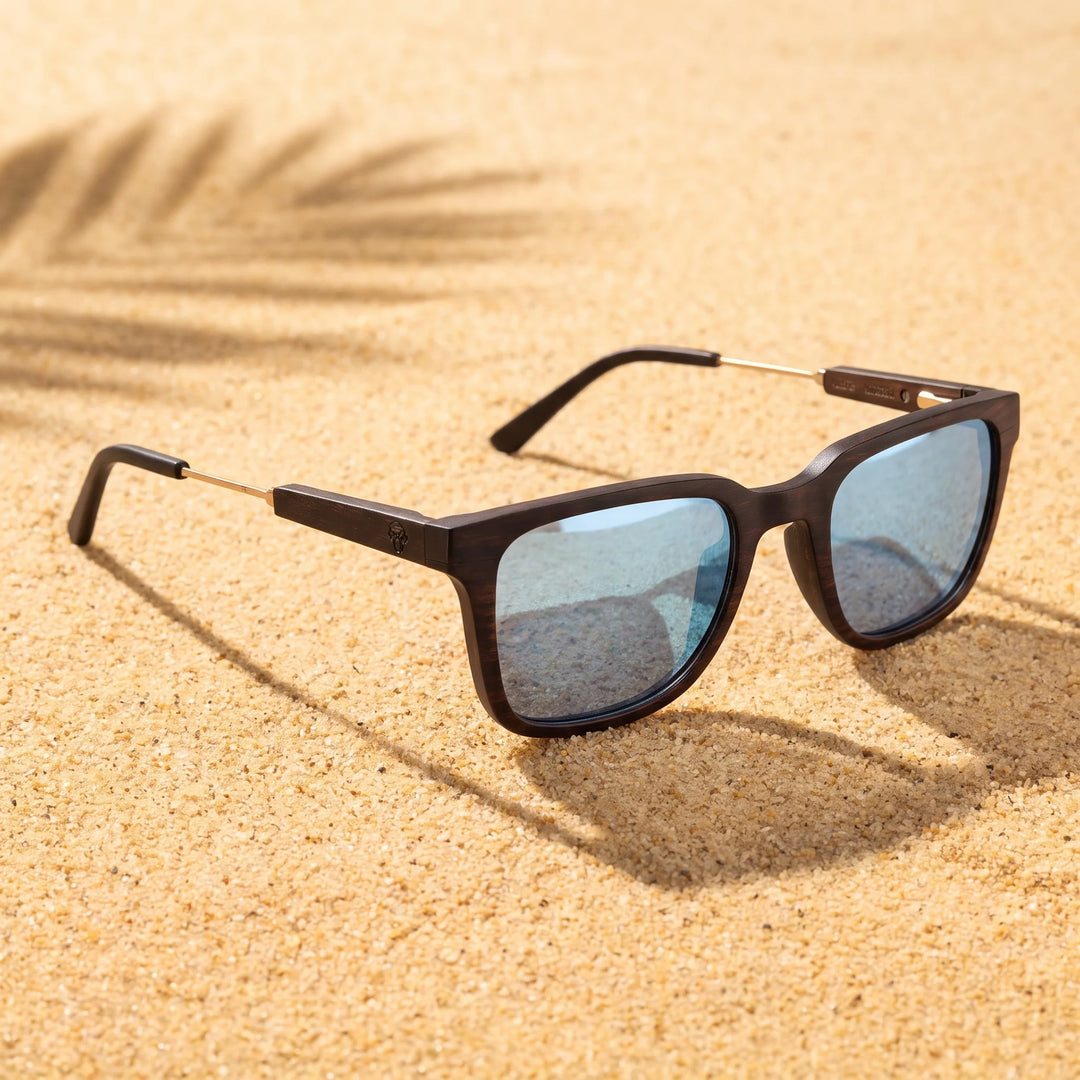 Lentes sol Thanos Ébano Natural UV400 sobre arena dorada costa textura natural Bonoboss #color_espejado-azul-ice