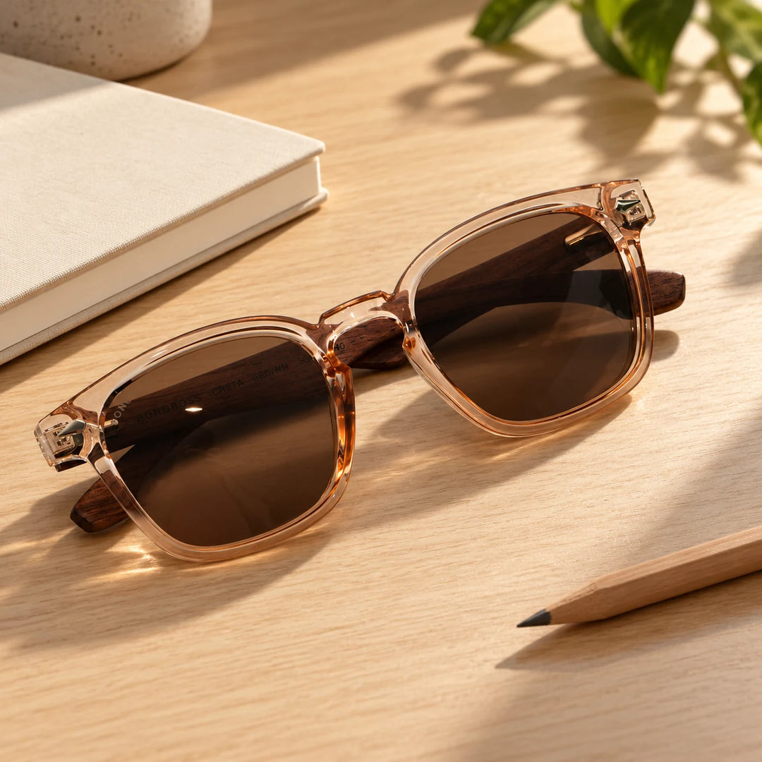 Lentes de sol Bonoboss Creta Brown sobre madera y rocas junto al mar al atardecer #editorial_grid2 #color_brown
