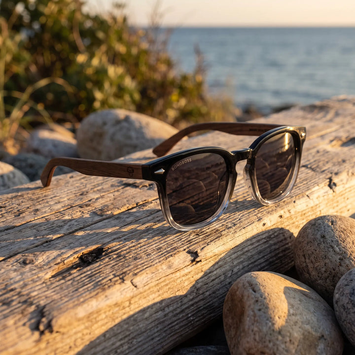 Lentes de sol Bonoboss Creta Negro sobre madera y rocas junto al mar al atardecer #editorial_grid2 #color_negro