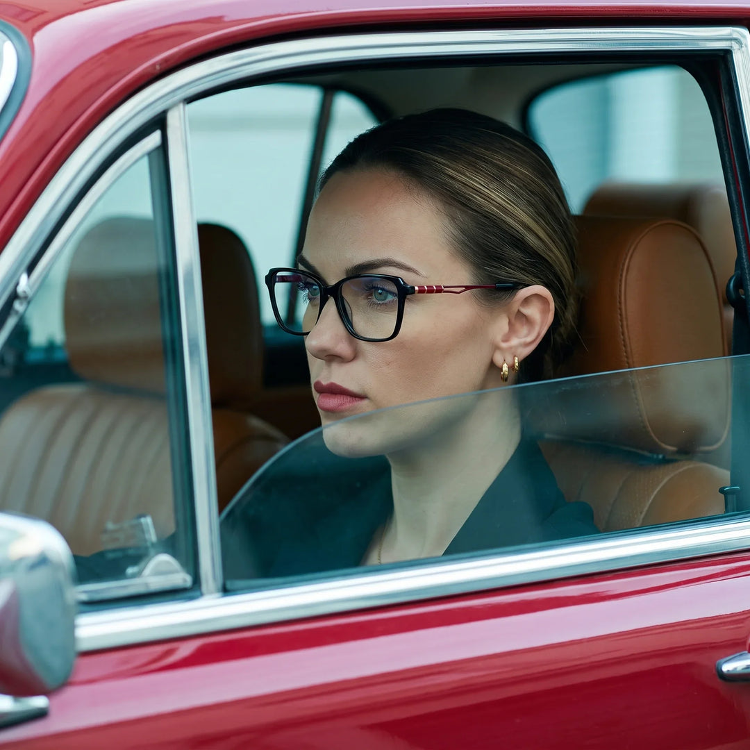 Anteojos Fiore 1006 en negro, en modelo – retrato de campaña, mirada a través de la ventana de un auto clásico rojo