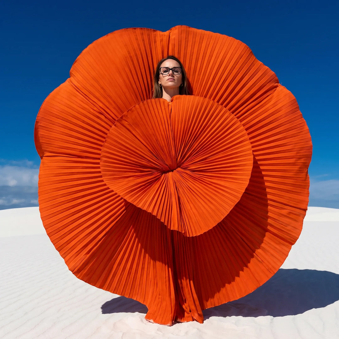 Anteojos Fiore 1006 en negro, en modelo – retrato de campaña, abanico plisado naranja escultórico sobre dunas blancas