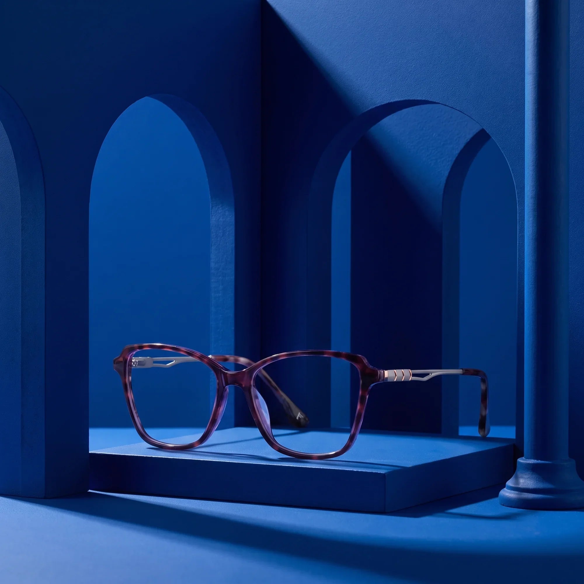 Anteojos Fiore 1006 en morado – staged on a sculptural cobalt architecture set