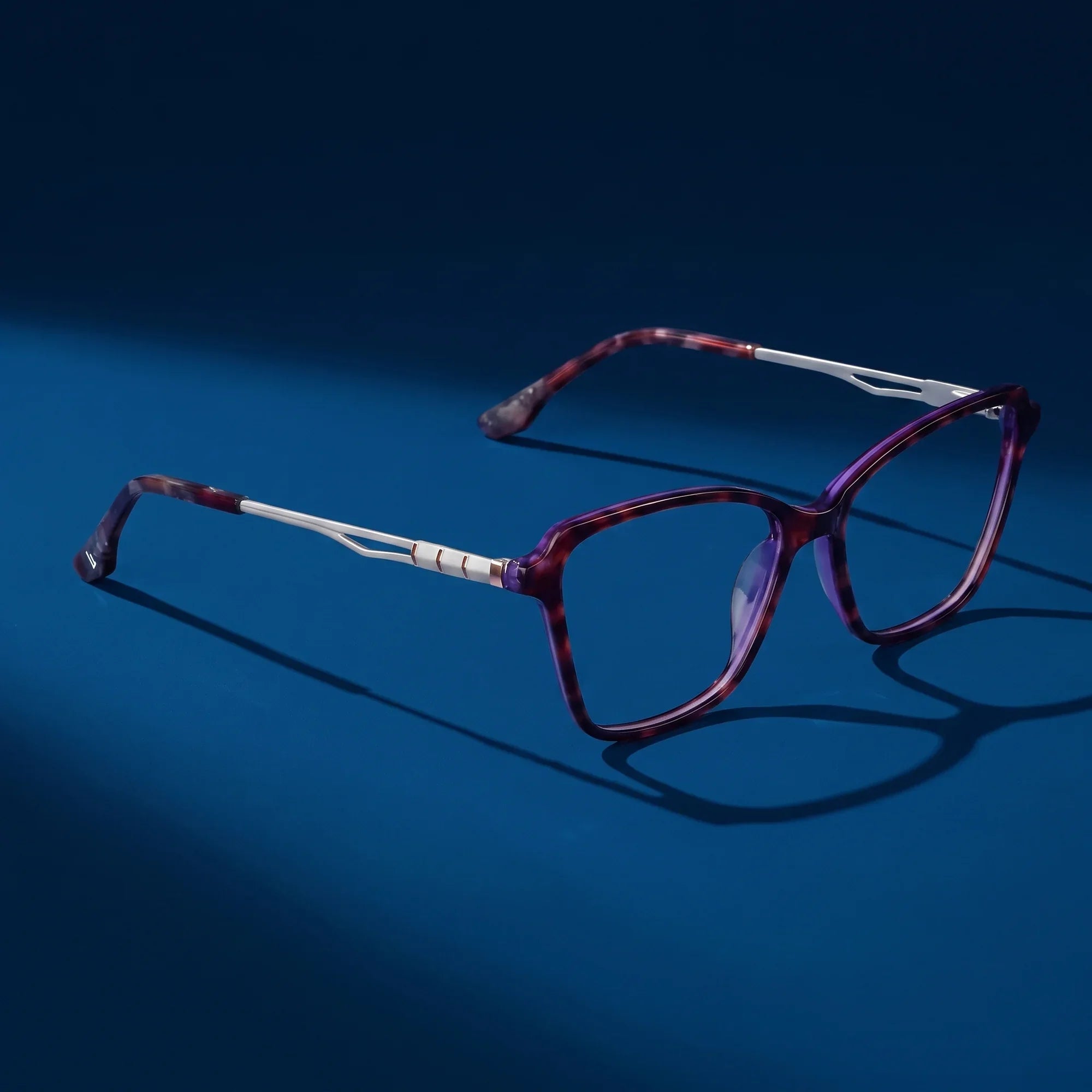 Anteojos Fiore 1006 en morado – hero still life against a deep midnight blue backdrop