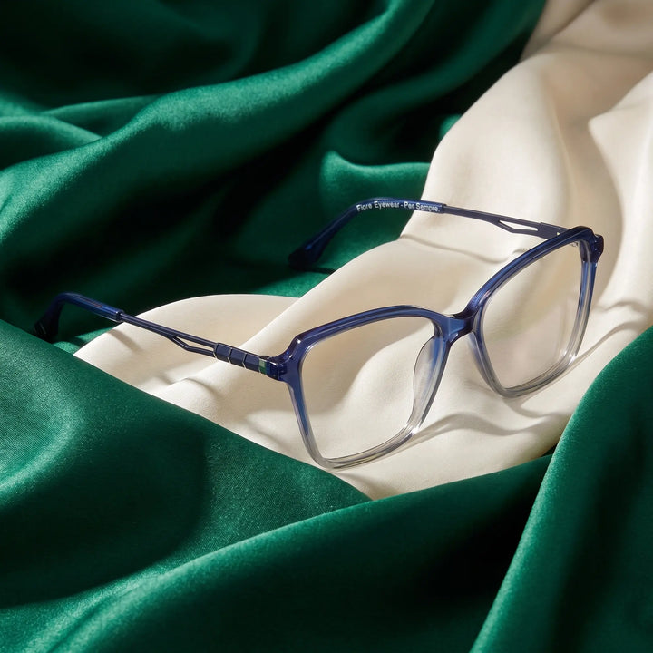 Anteojos Fiore 1006 en azul – resting on draped emerald and ivory silk