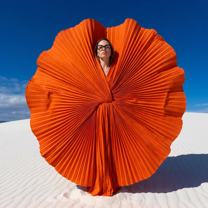 Anteojos Fiore 1010 en negro, en modelo – retrato de campaña, abanico plisado naranja escultórico sobre dunas blancas
