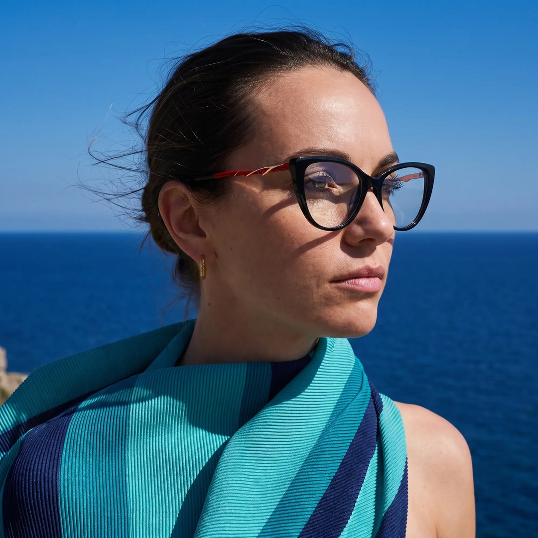 Anteojos Fiore 1010 en negro, en modelo – retrato de campaña, retrato al viento sobre el mar azul profundo