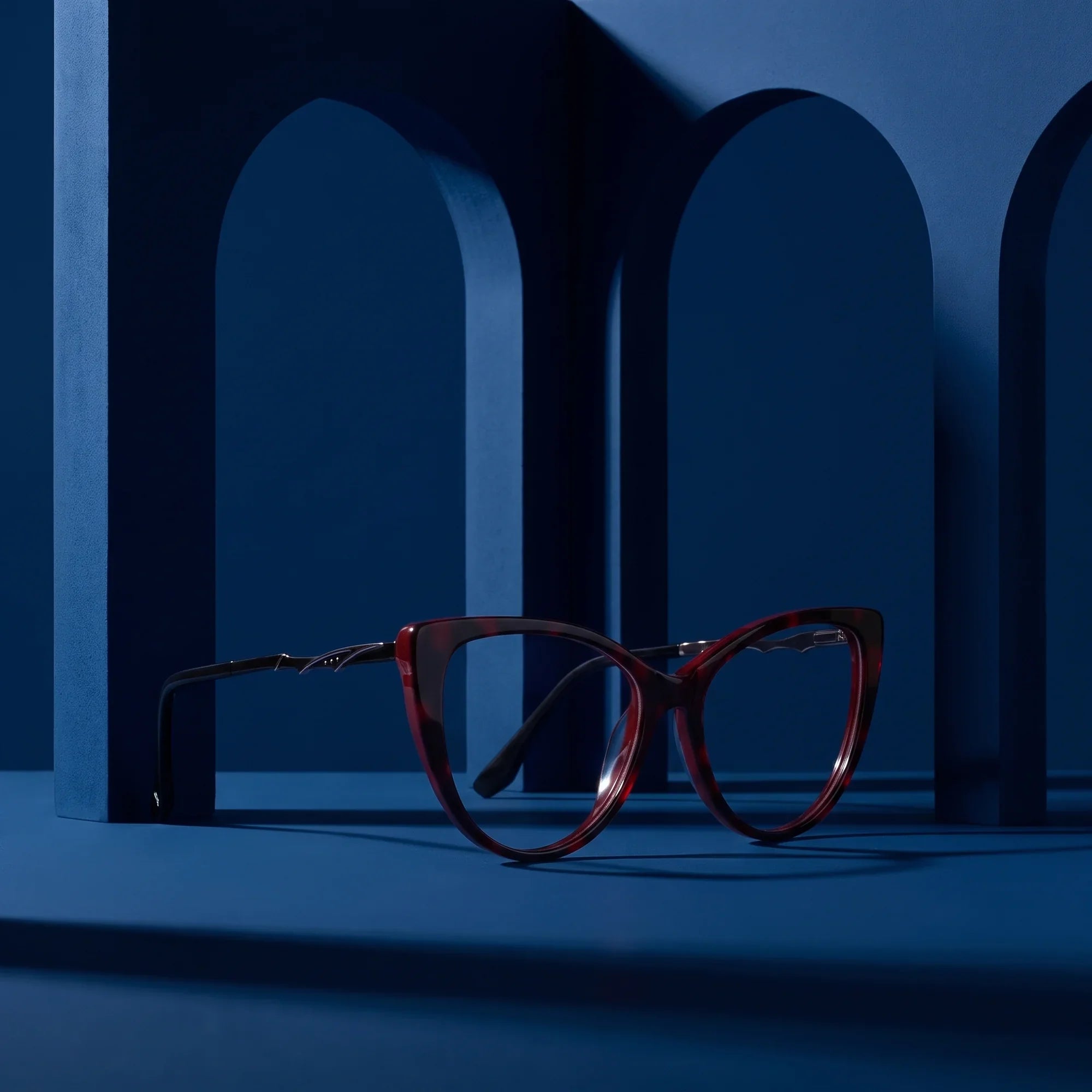 Anteojos Fiore 1010 en rojo – staged on a sculptural midnight blue architecture set