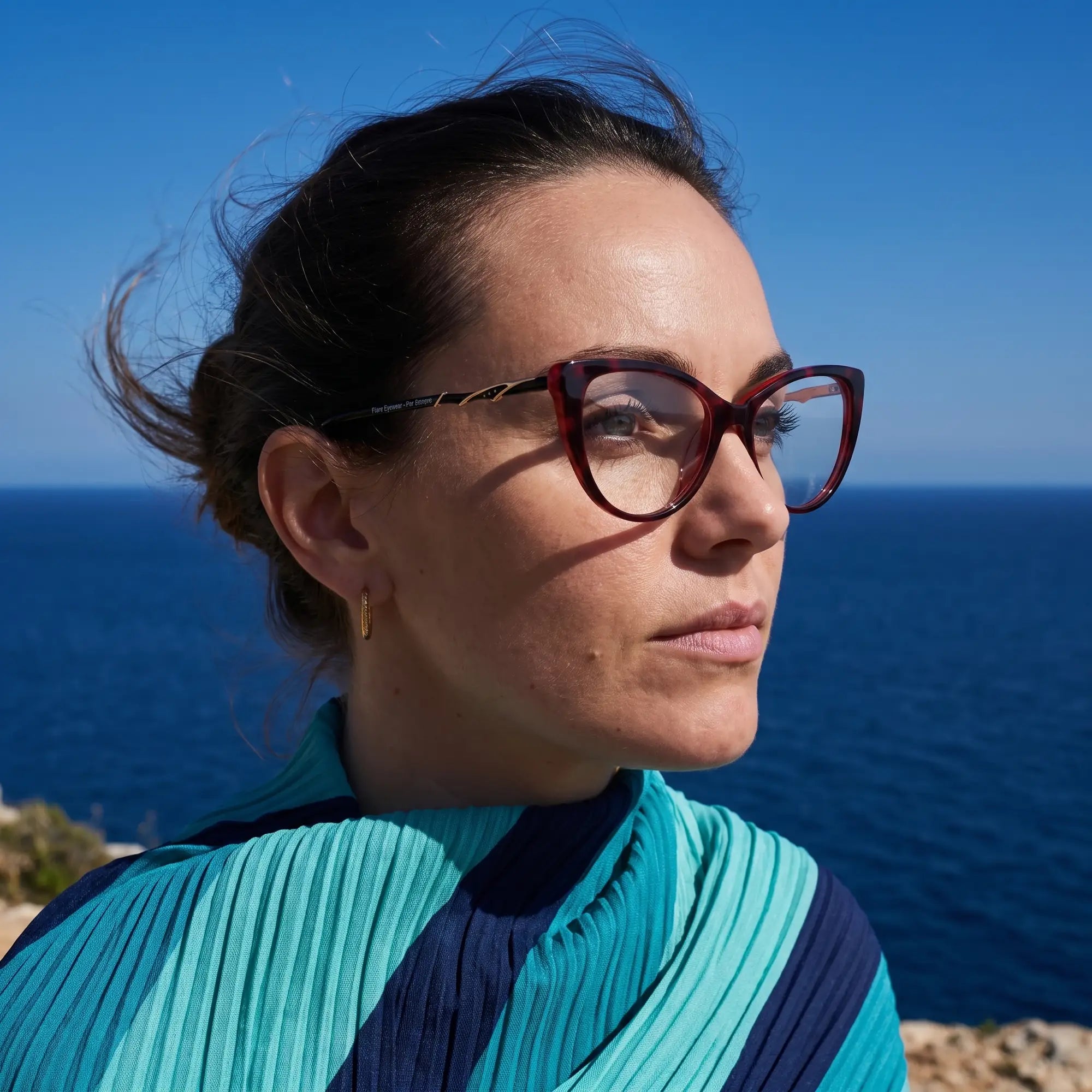 Anteojos Fiore 1010 en rojo, en modelo – retrato de campaña, retrato al viento sobre el mar azul profundo