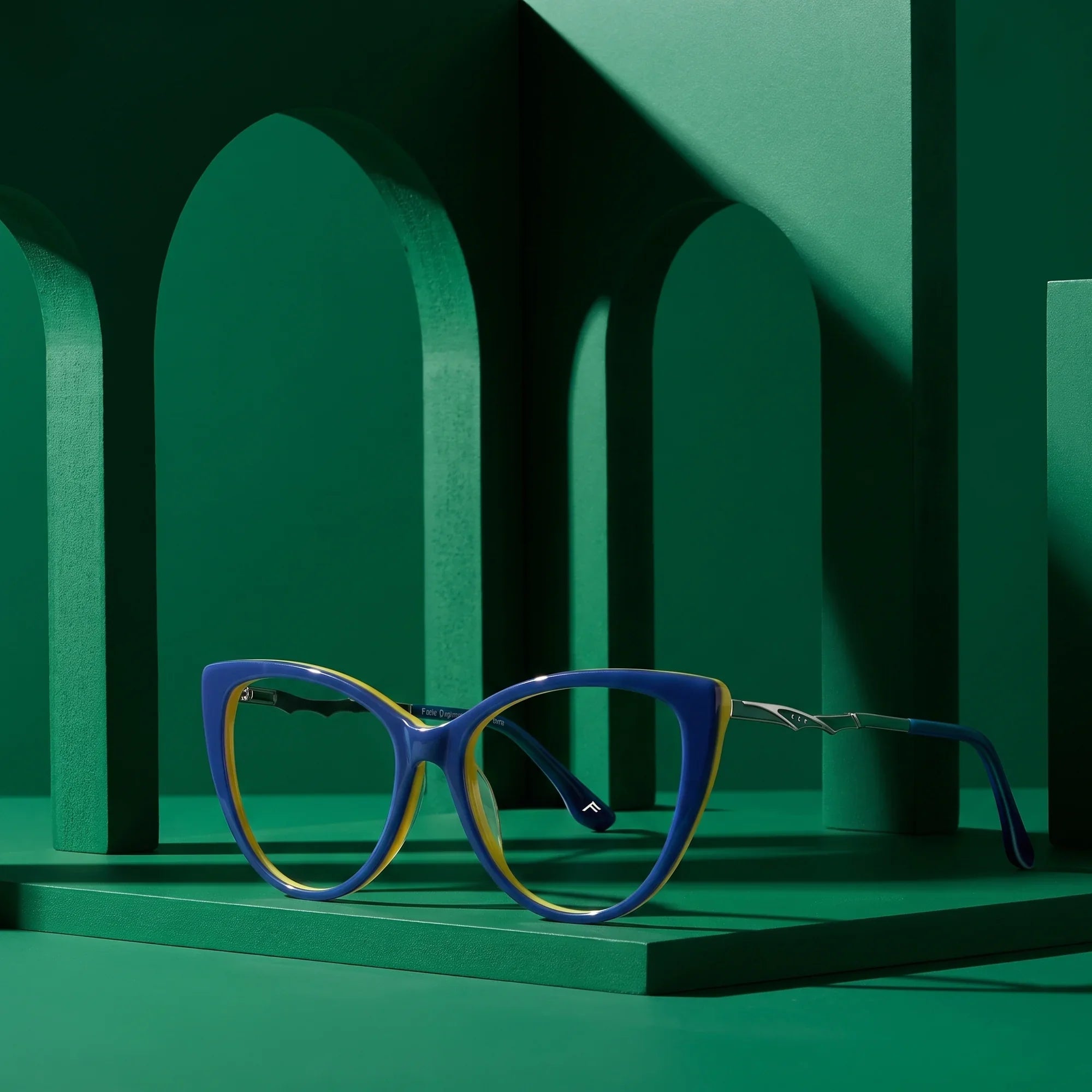 Anteojos Fiore 1010 en blue green – staged on a sculptural emerald architecture set