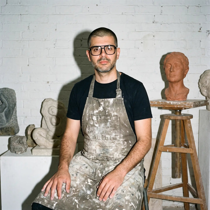 Anteojos Fiore 1014 en negro, en modelo – retrato de campaña, sculptor portrait among clay busts in a workshop