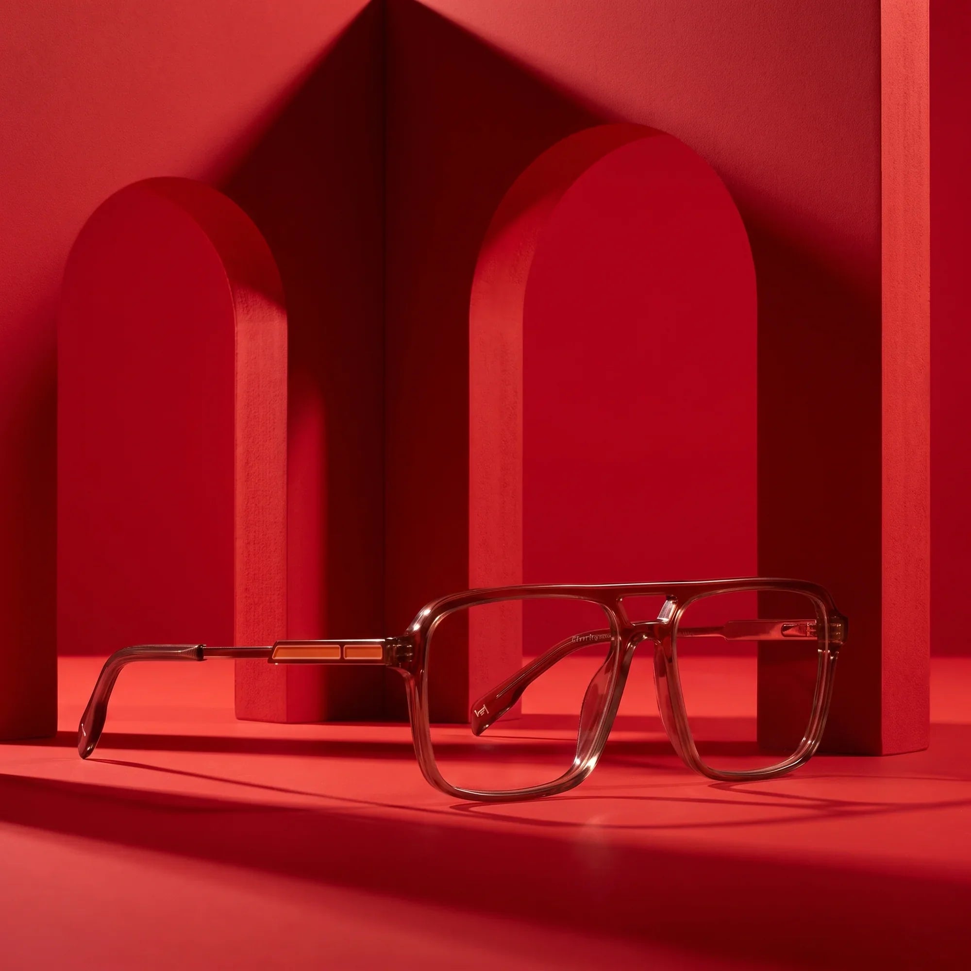 Anteojos Fiore 1014 en café – displayed on a vivid red podium among arches