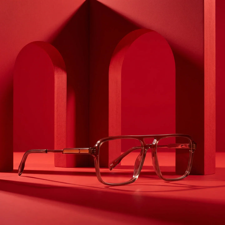 Anteojos Fiore 1014 en café – displayed on a vivid red podium among arches