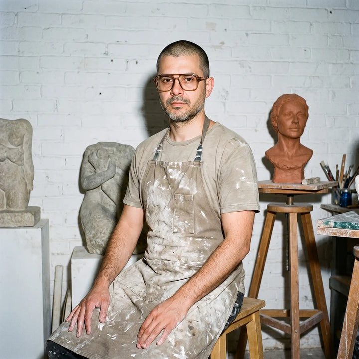 Anteojos Fiore 1014 en café, en modelo – retrato de campaña, sculptor portrait among clay busts in a workshop
