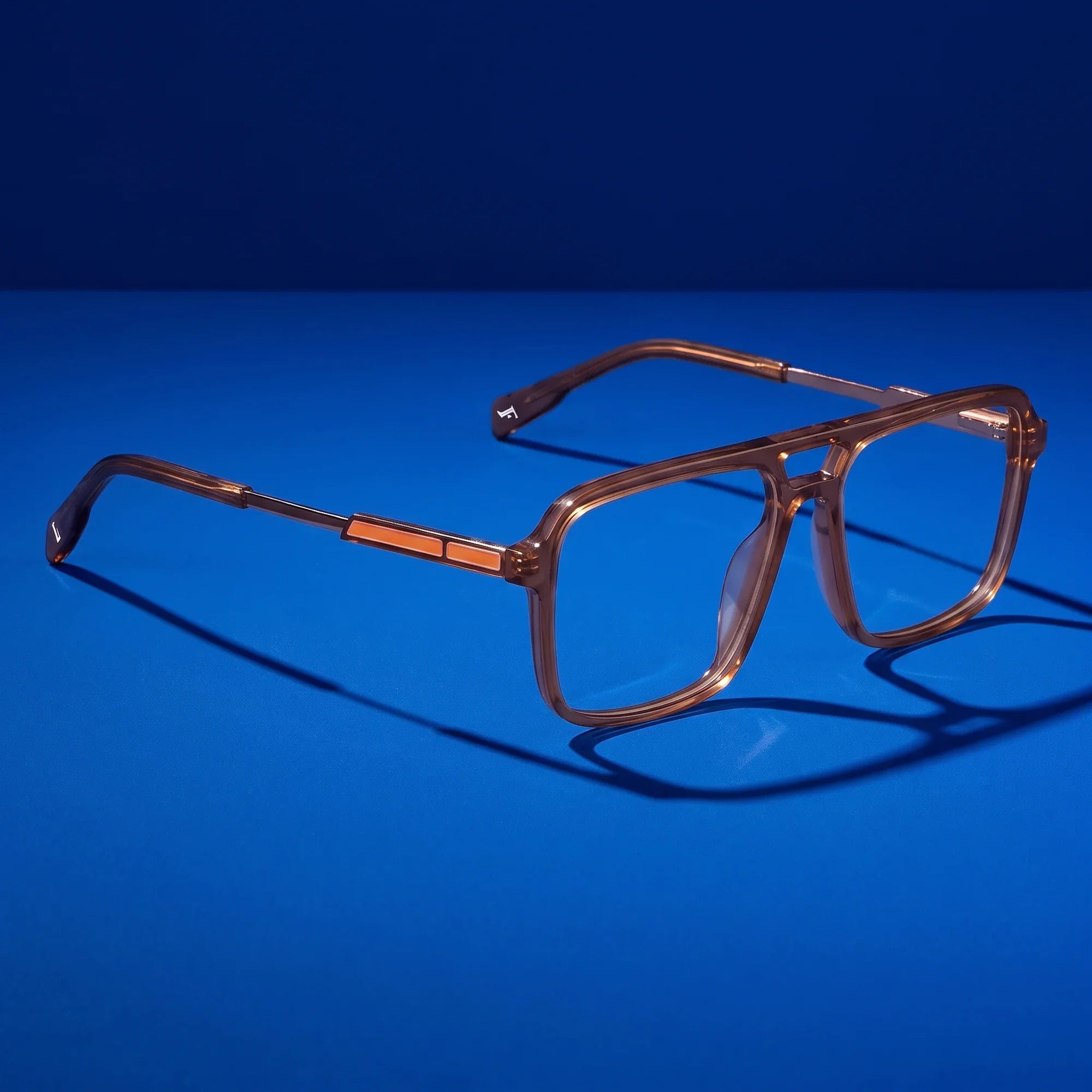 Anteojos Fiore 1014 en café – hero still life against a deep cobalt backdrop