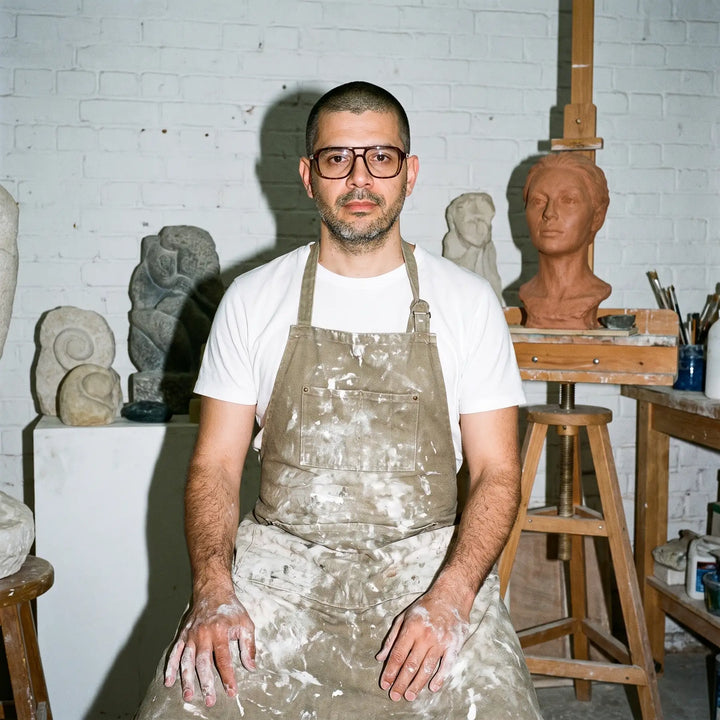 Anteojos Fiore 1014 en tortoiseshell, en modelo – retrato de campaña, sculptor portrait among clay busts in a workshop