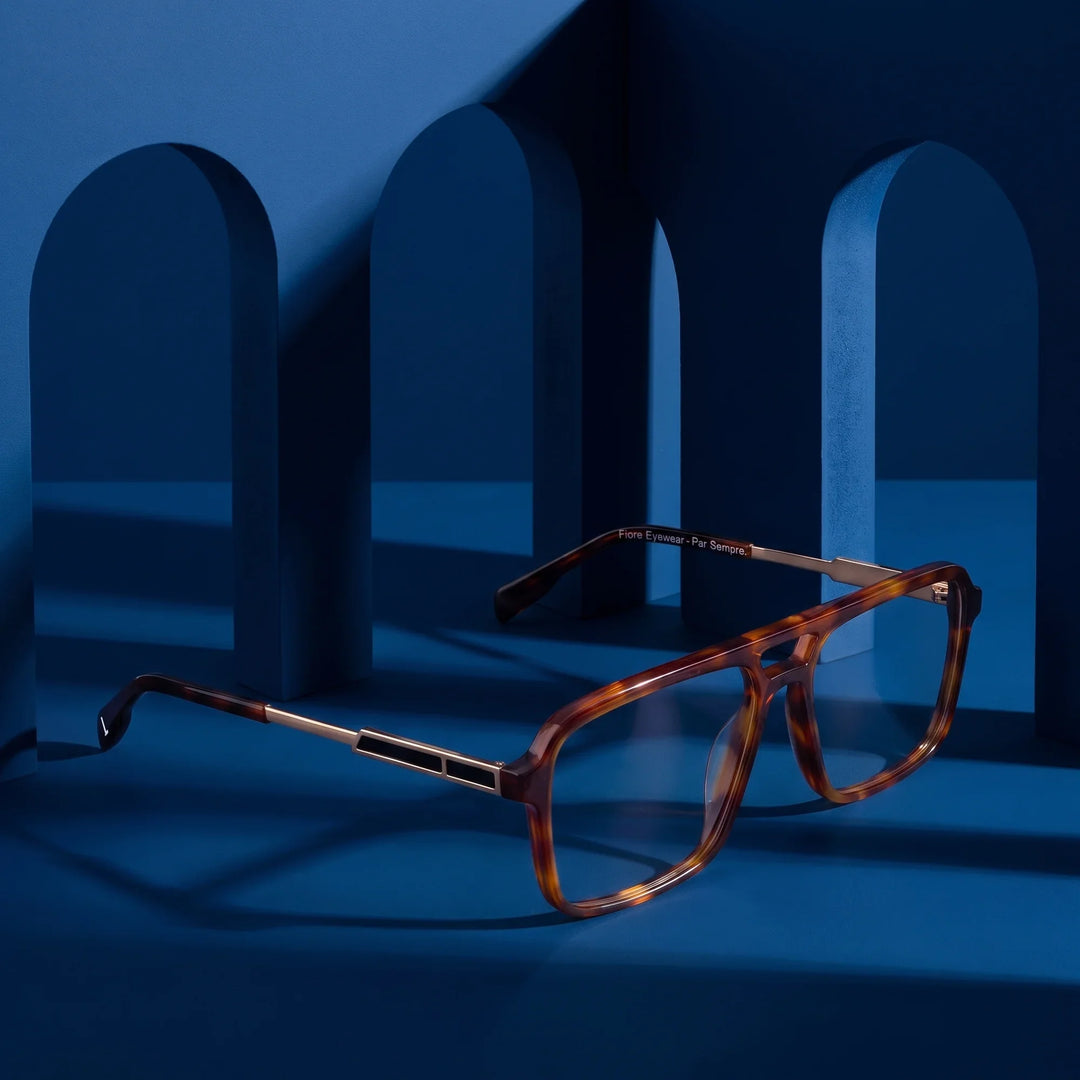 Anteojos Fiore 1014 en brown tortoiseshell – exhibido en un podio azul medianoche entre arcos