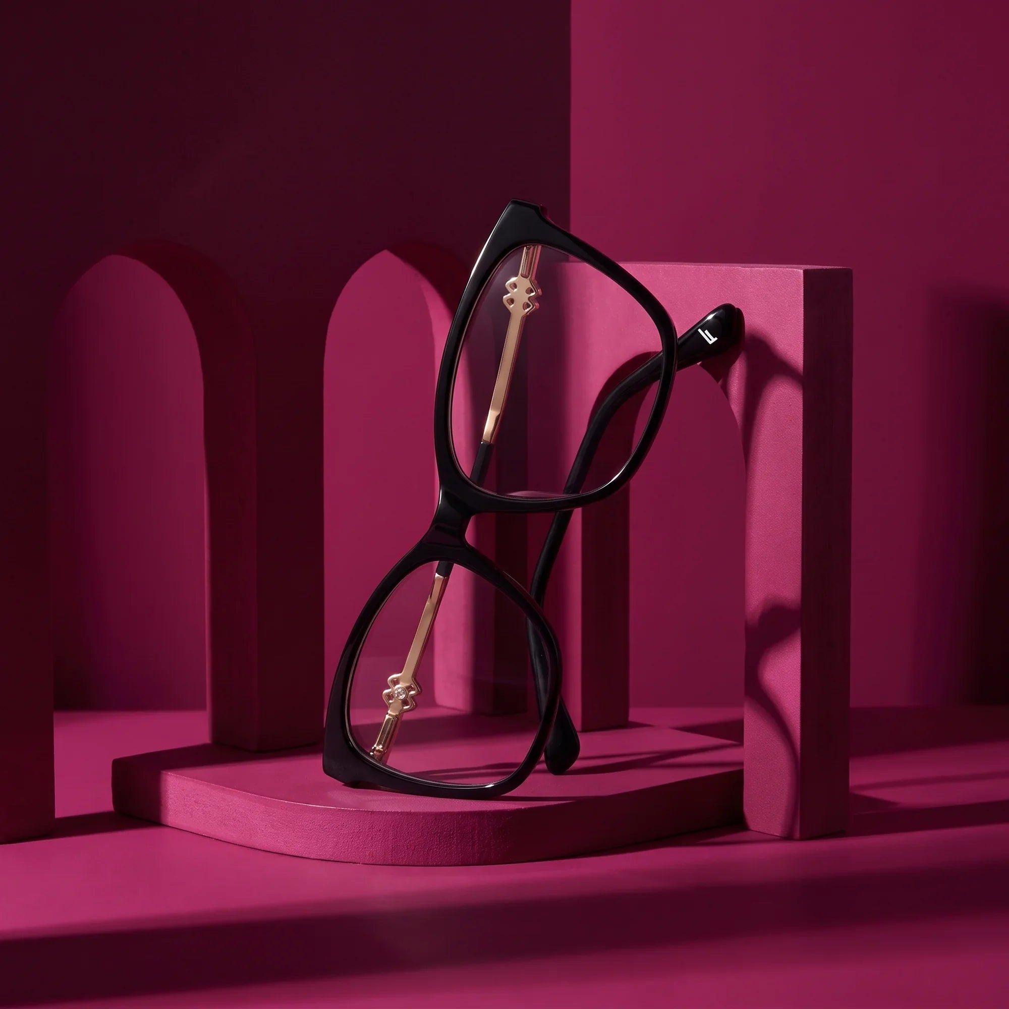 Anteojos Fiore 10172 en negro – staged on a sculptural magenta architecture set