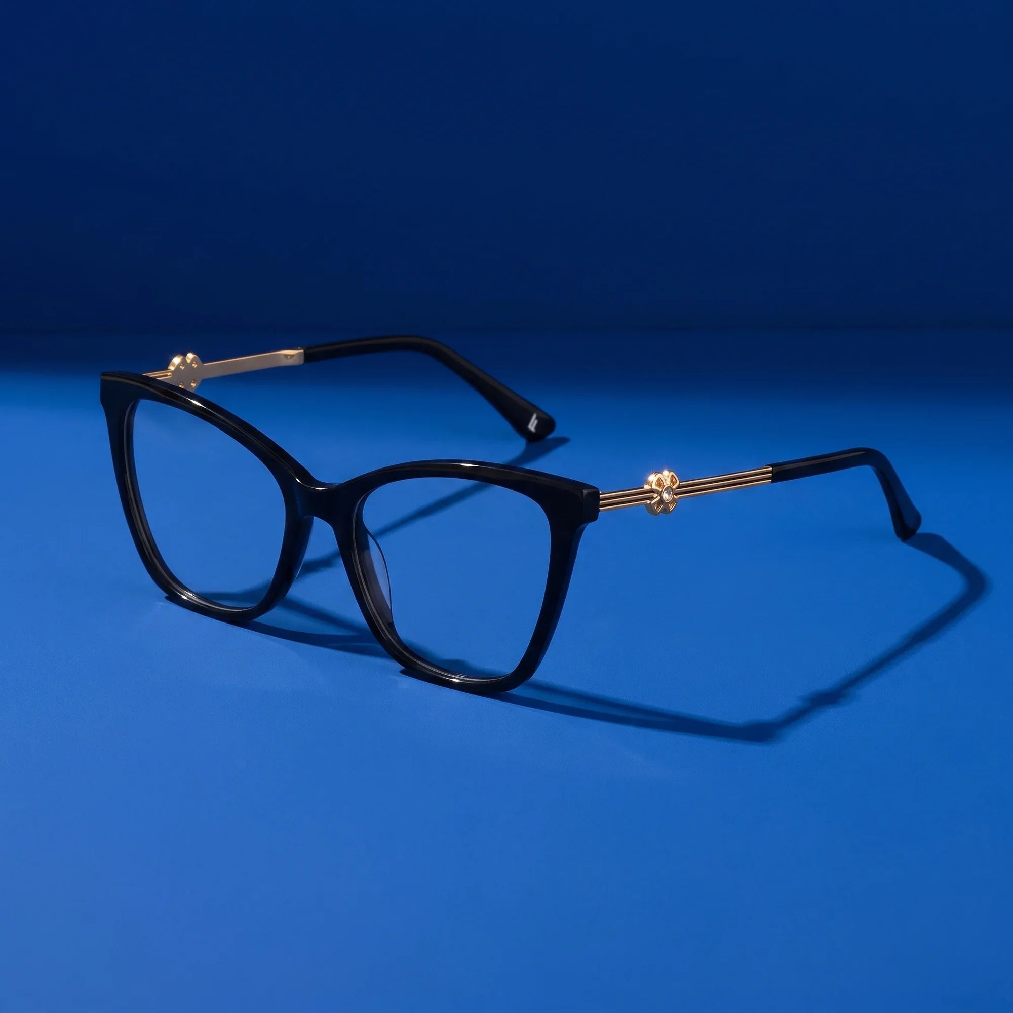 Anteojos Fiore 10172 en negro – hero still life against a deep cobalt backdrop