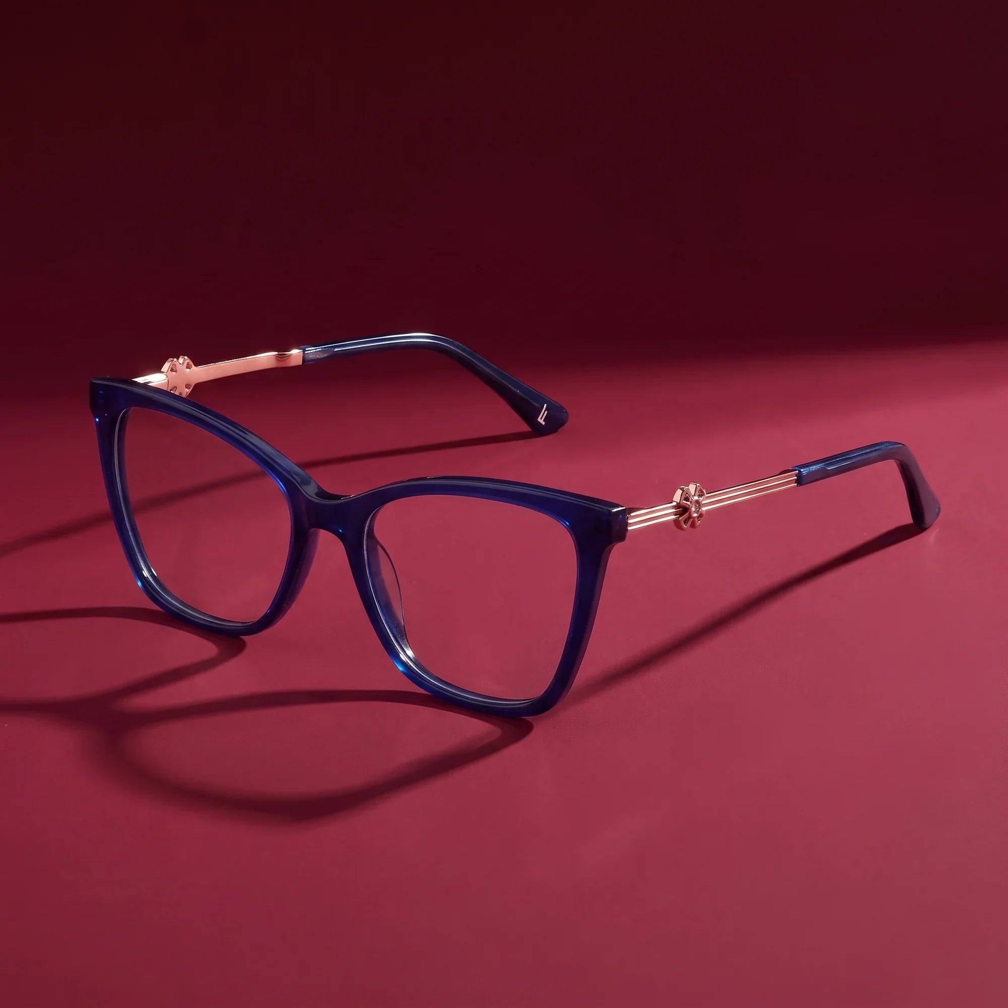 Anteojos Fiore 10172 en azul – hero still life against a deep burgundy backdrop