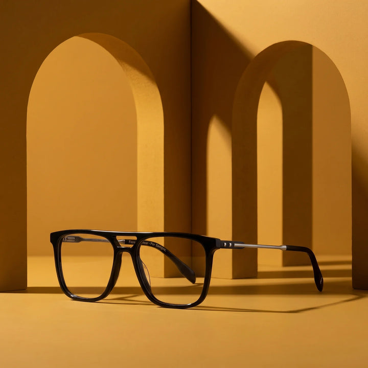 Anteojos Fiore 10177 en negro – displayed on a mustard ochre podium among arches