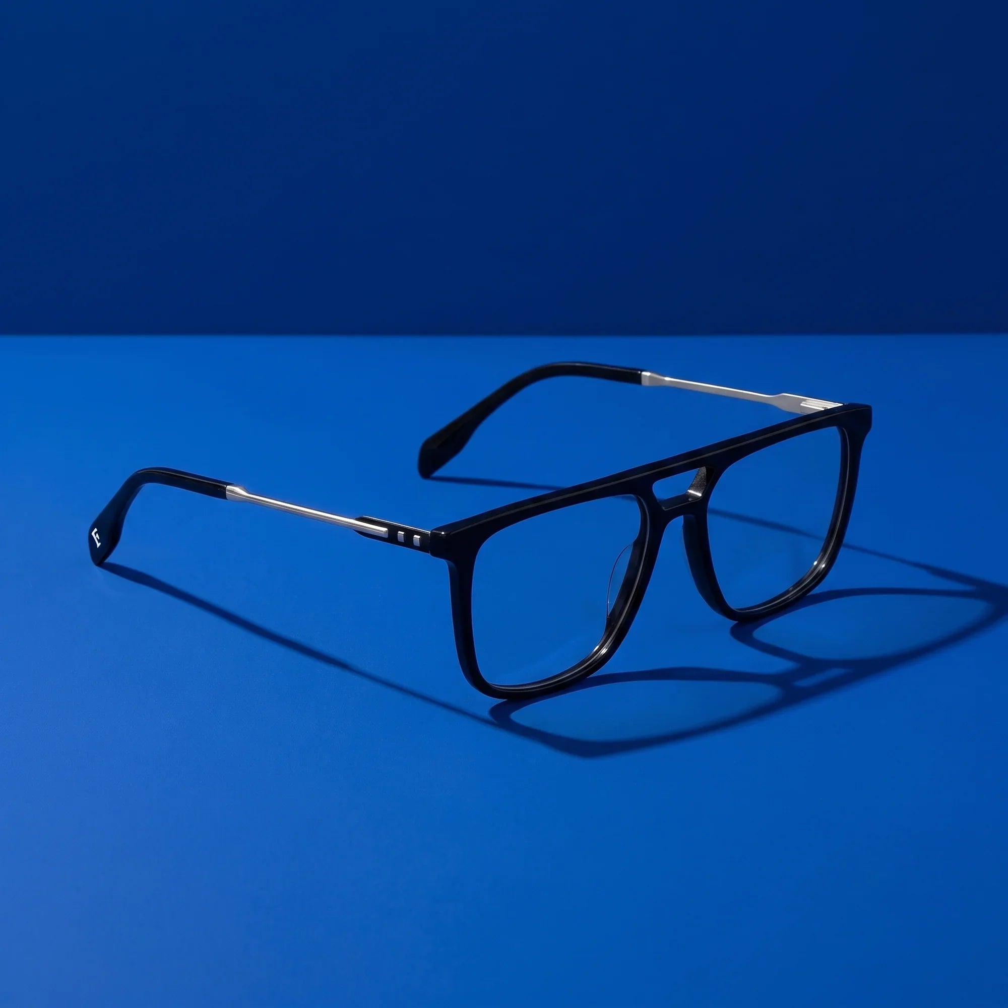 Anteojos Fiore 10177 en negro – hero still life against a deep cobalt backdrop