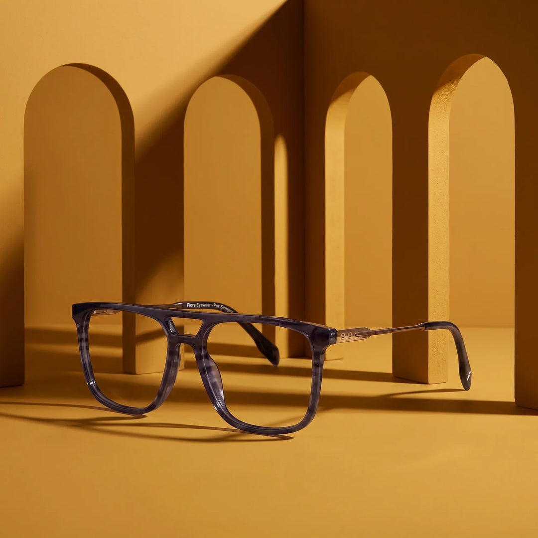 Anteojos Fiore 10177 en gris – displayed on a mustard ochre podium among arches