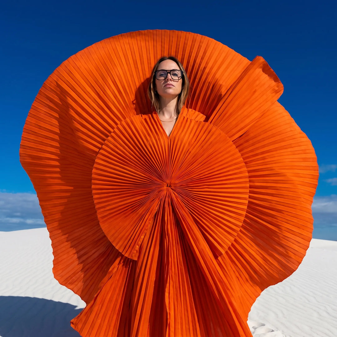 Anteojos Fiore 10177 en gris, en modelo – retrato de campaña, abanico plisado naranja escultórico sobre dunas blancas