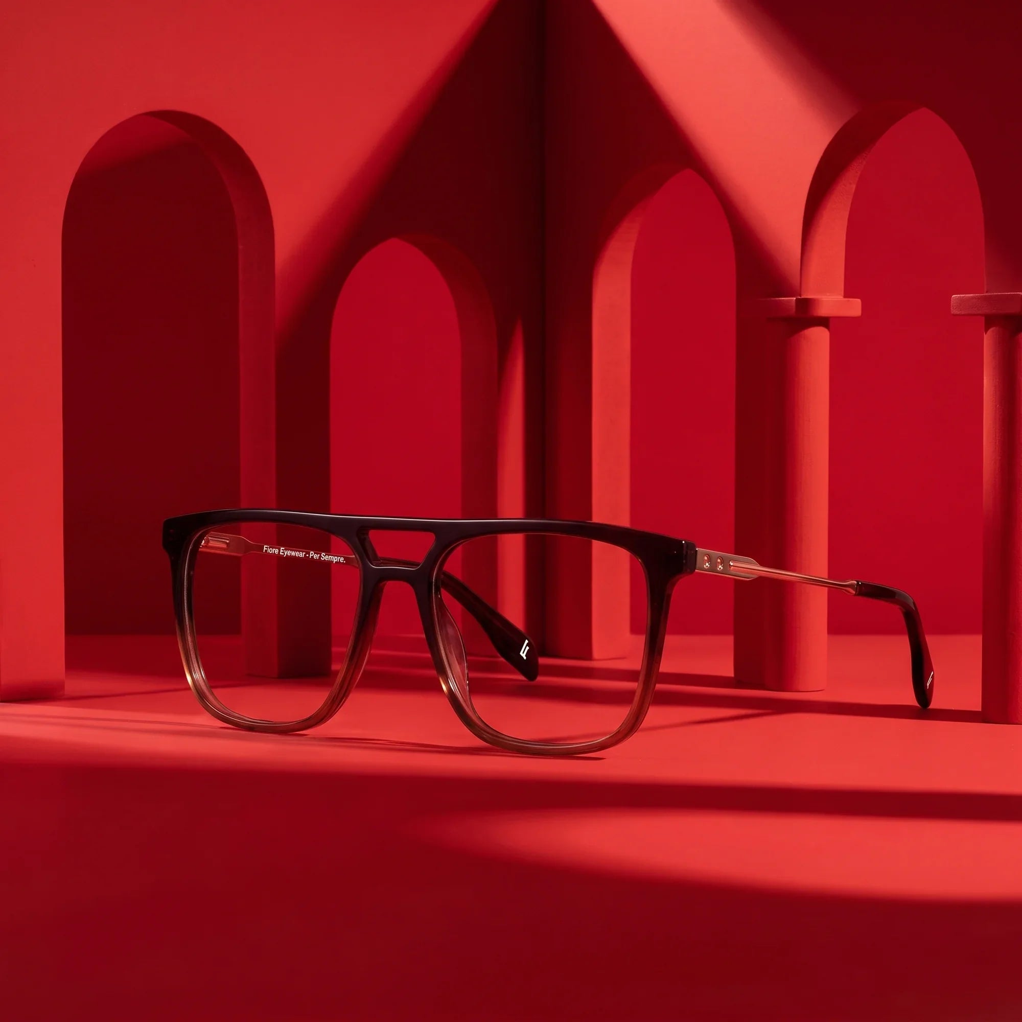 Anteojos Fiore 10177 en café – staged on a sculptural vivid red architecture set
