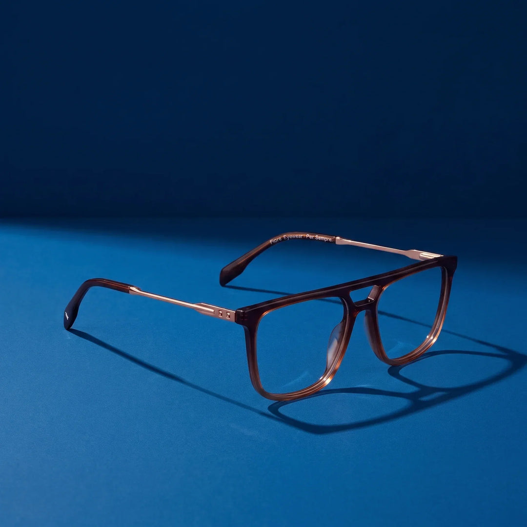 Anteojos Fiore 10177 en café – hero still life against a deep midnight blue backdrop
