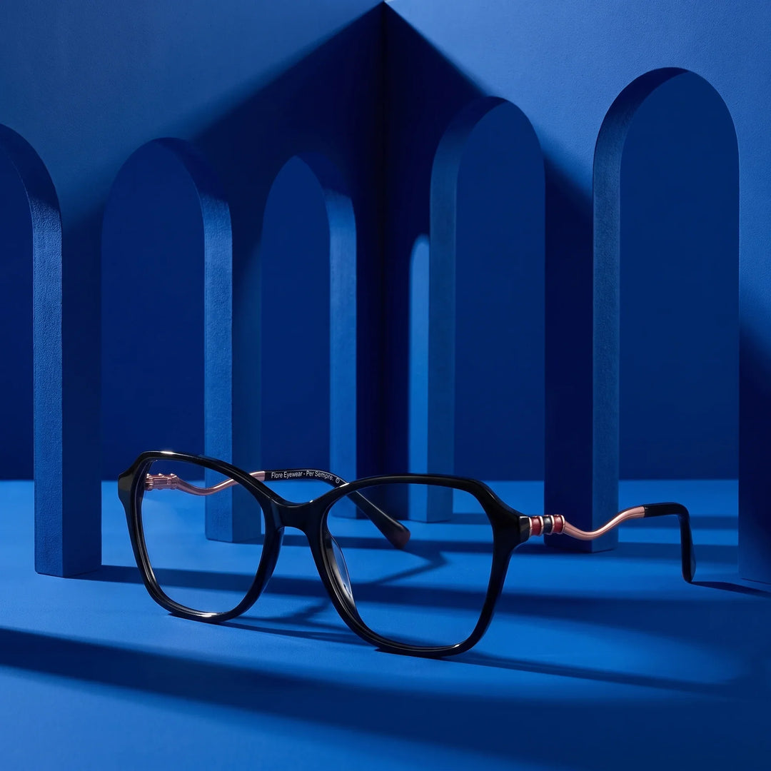 Anteojos Fiore 1030 en negro – displayed on a cobalt podium among arches