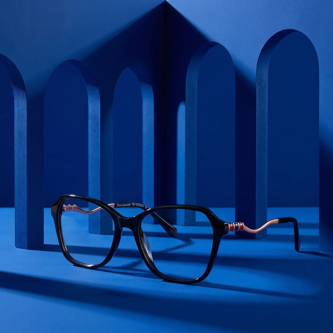 Anteojos Fiore 1030 en negro – displayed on a cobalt podium among arches