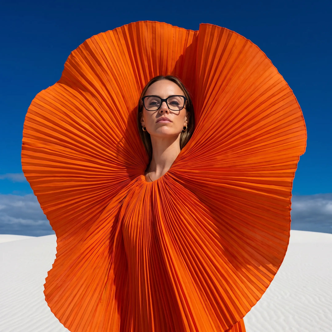 Anteojos Fiore 1030 en negro, en modelo – retrato de campaña, abanico plisado naranja escultórico sobre dunas blancas