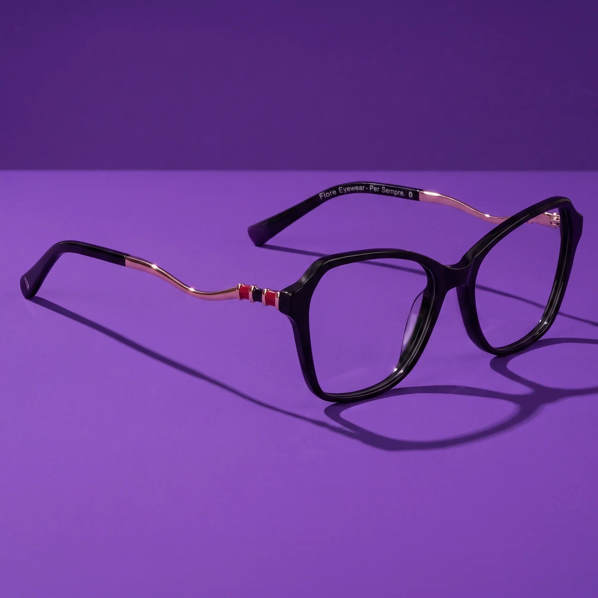 Anteojos Fiore 1030 en negro – hero still life against a deep violet backdrop