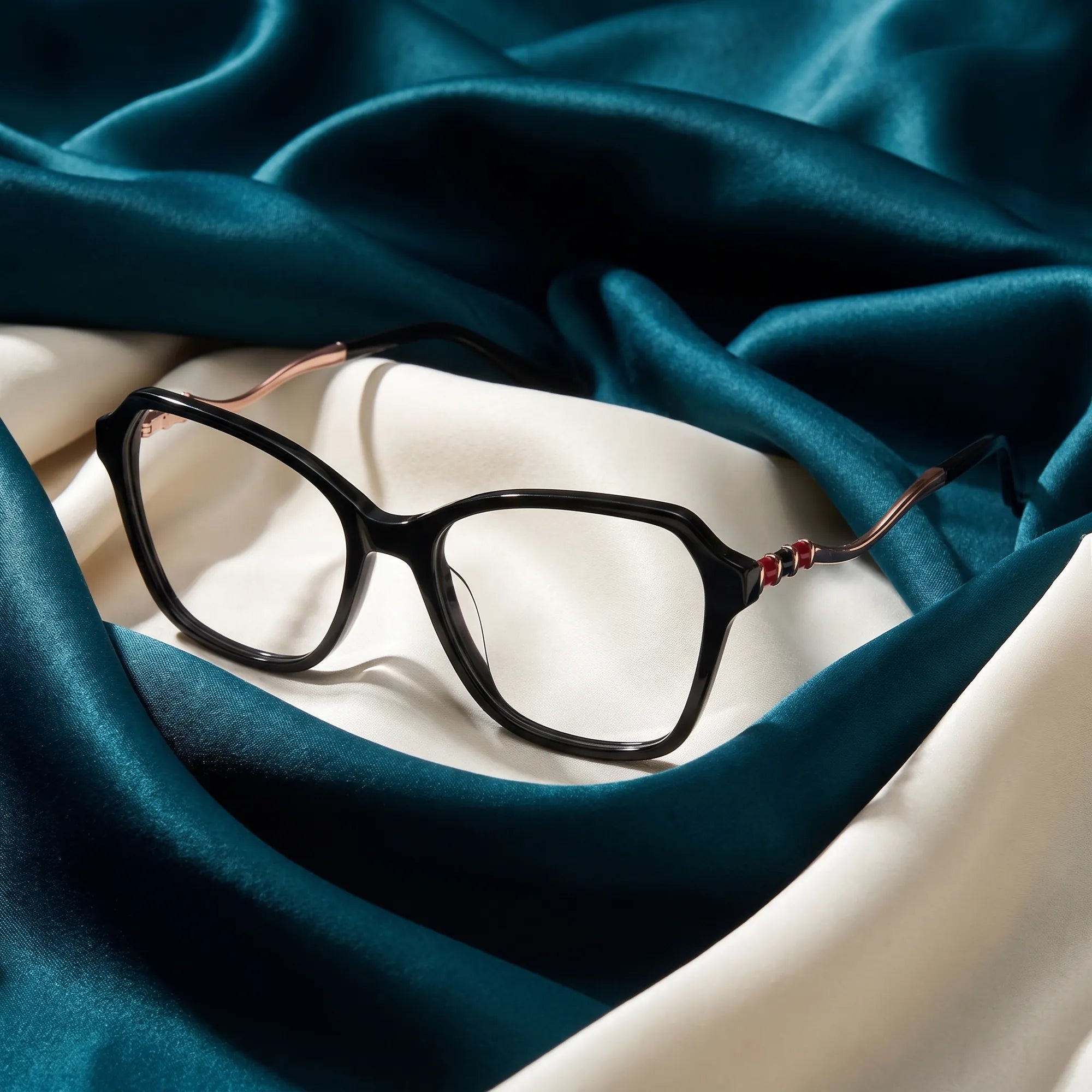 Anteojos Fiore 1030 en negro – resting on draped teal and ivory silk