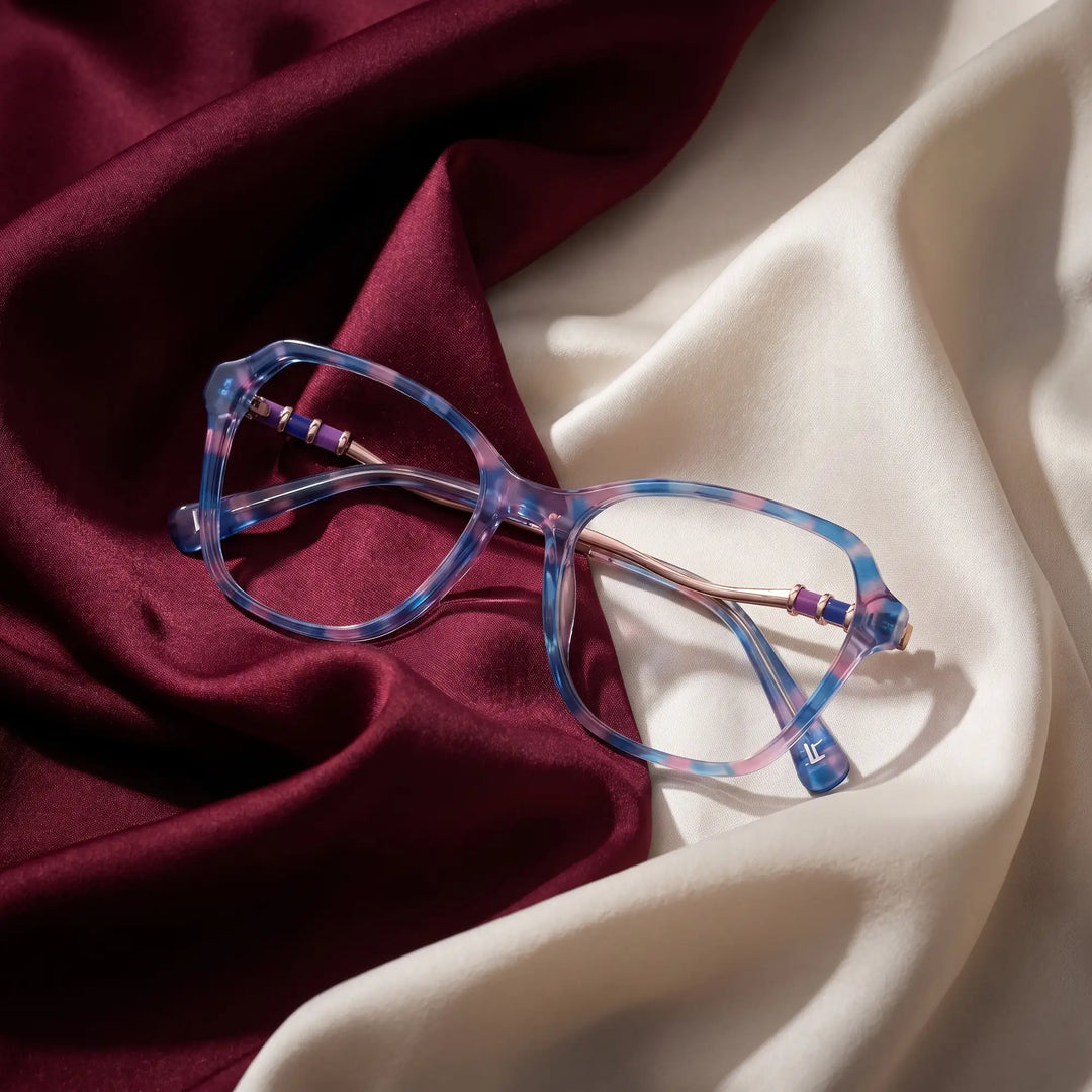 Anteojos Fiore 1030 en azul rosado – resting on draped burgundy and ivory silk