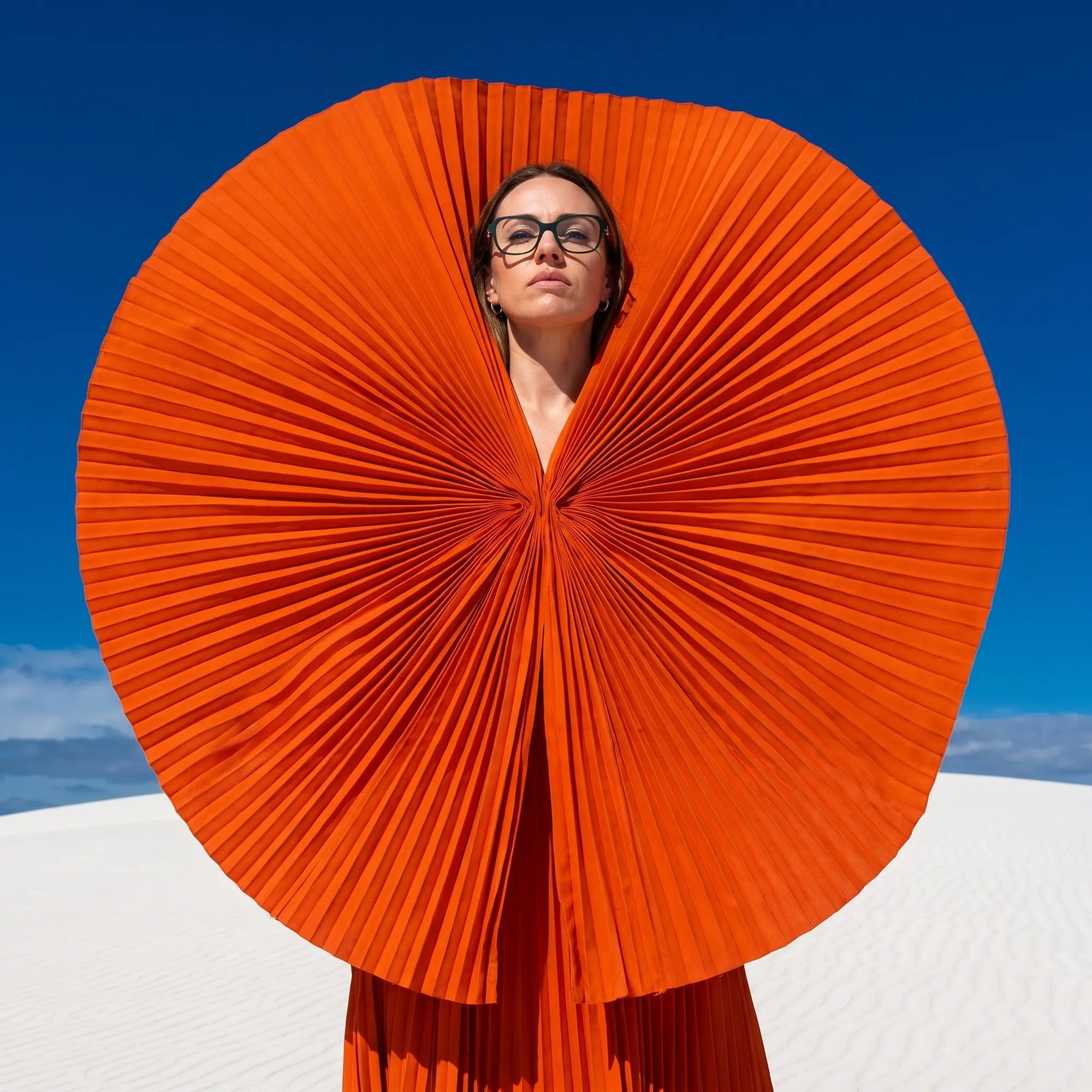 Anteojos Fiore 1030 en verde, en modelo – retrato de campaña, abanico plisado naranja escultórico sobre dunas blancas