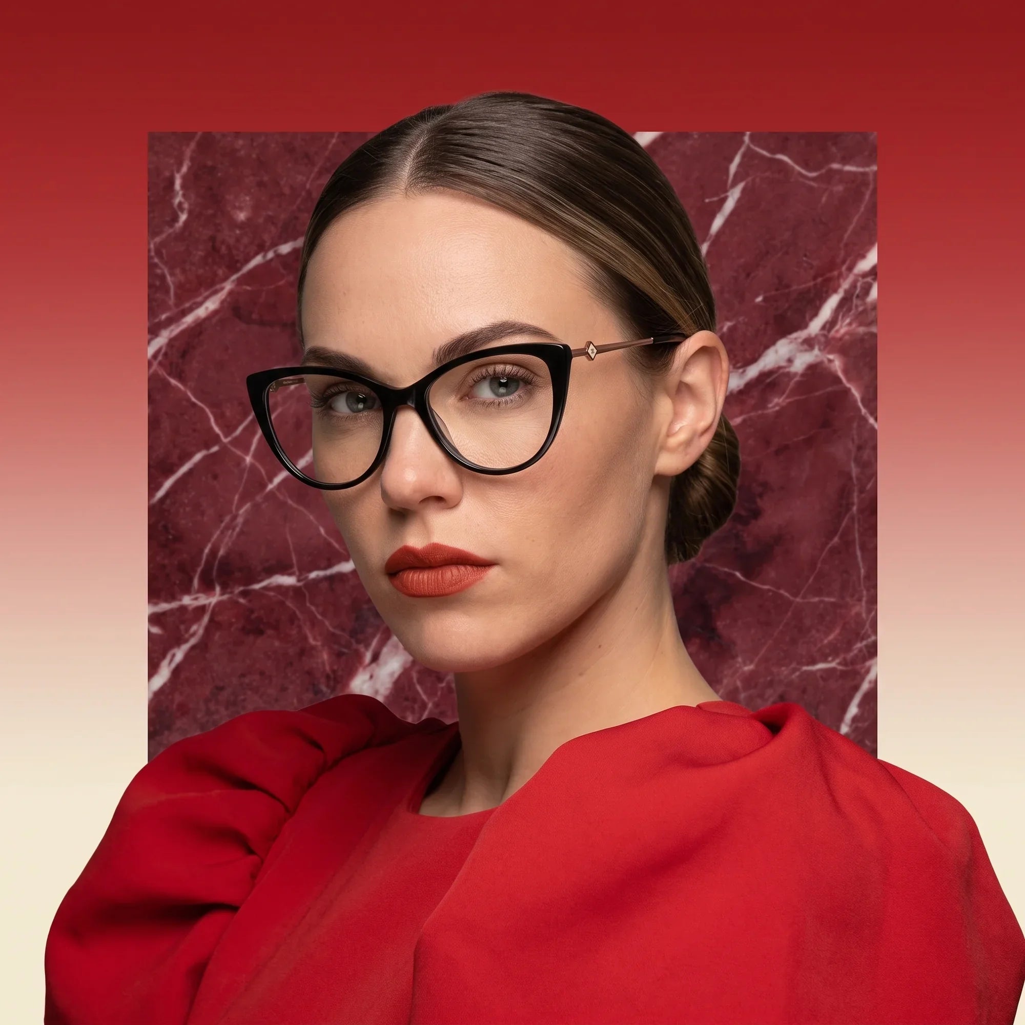 Anteojos Fiore 1031 en negro, en modelo – retrato de campaña, fondo de mármol rojo y vestido escarlata drapeado