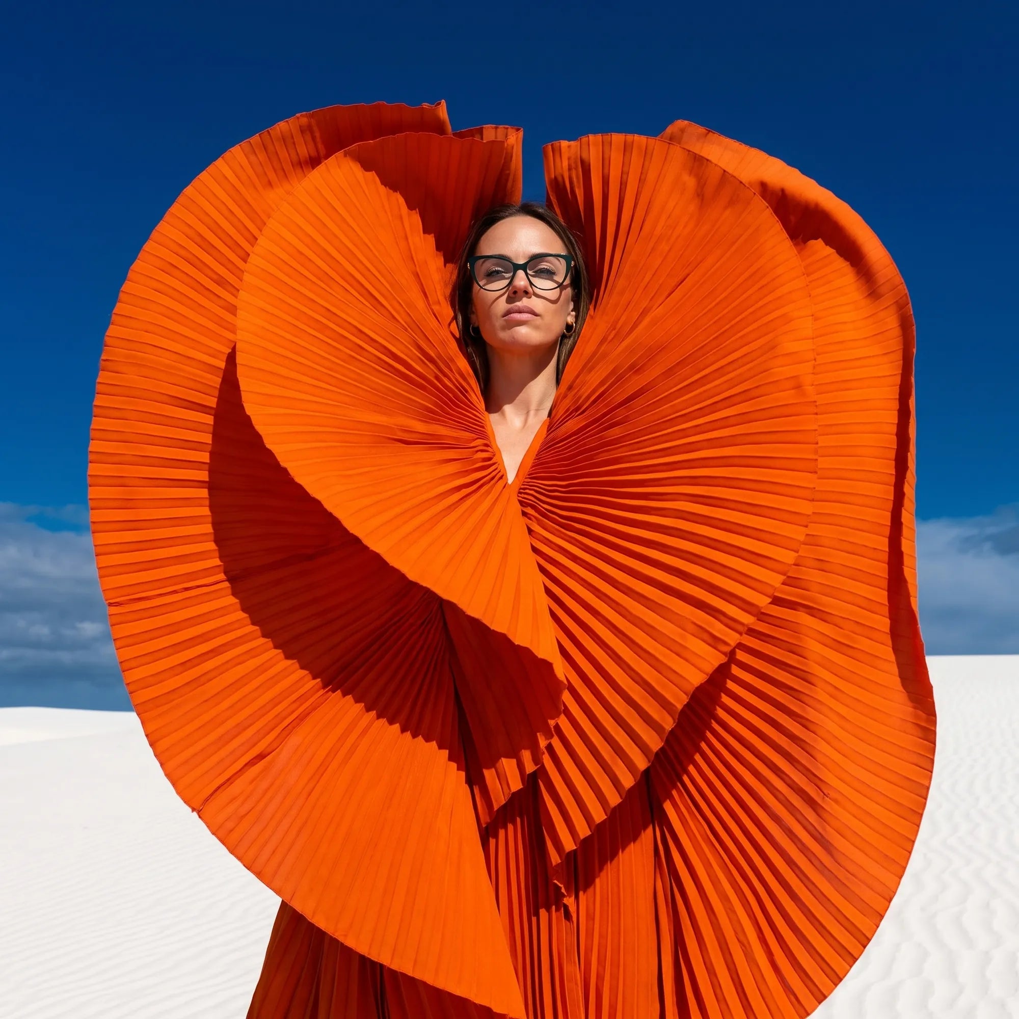 Anteojos Fiore 1031 en verde, en modelo – retrato de campaña, abanico plisado naranja escultórico sobre dunas blancas