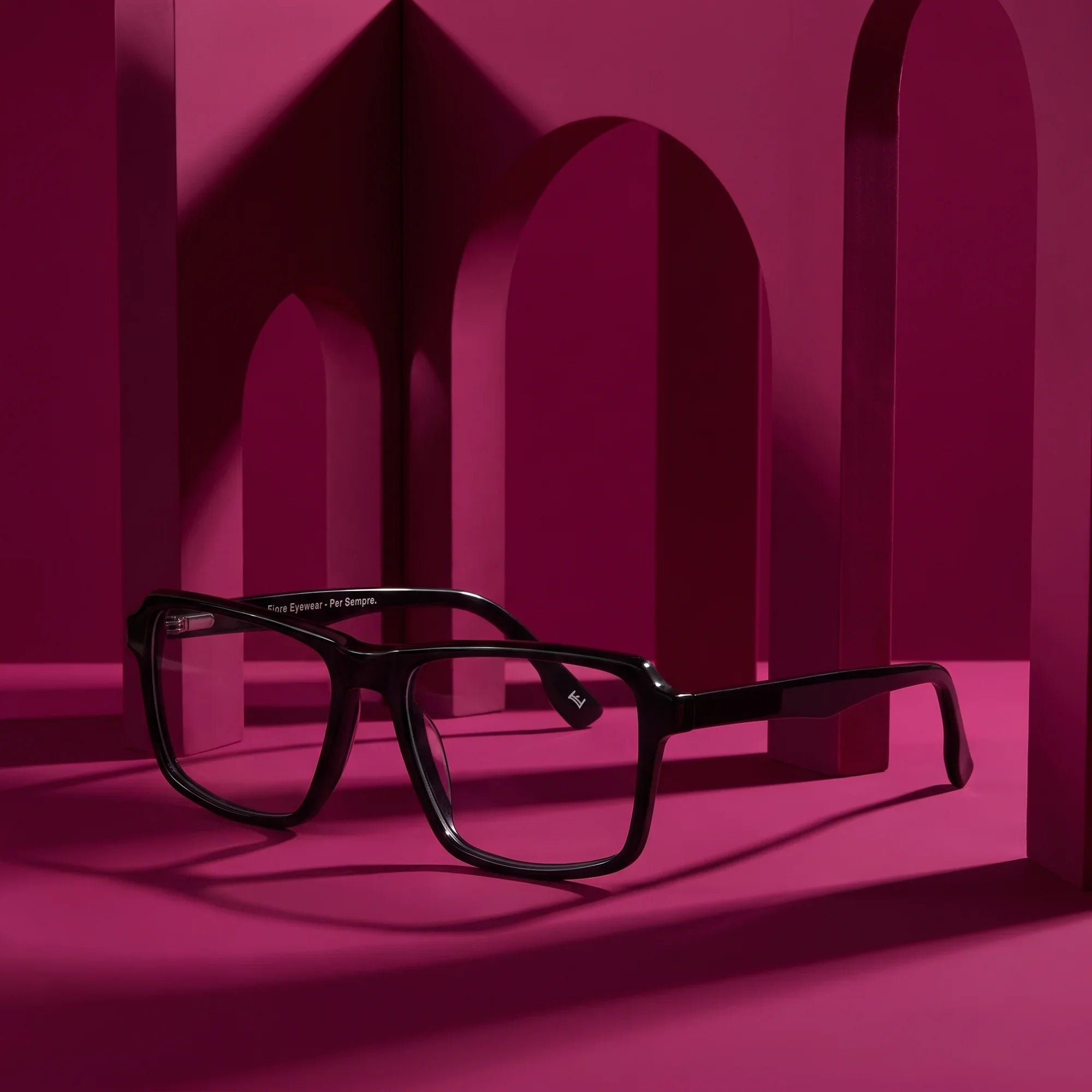 Anteojos Fiore 1038 en negro – staged on a sculptural magenta architecture set