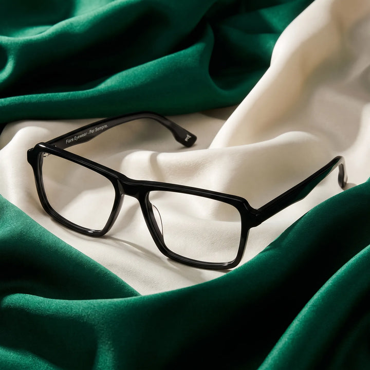 Anteojos Fiore 1038 en negro – resting on draped emerald and ivory silk