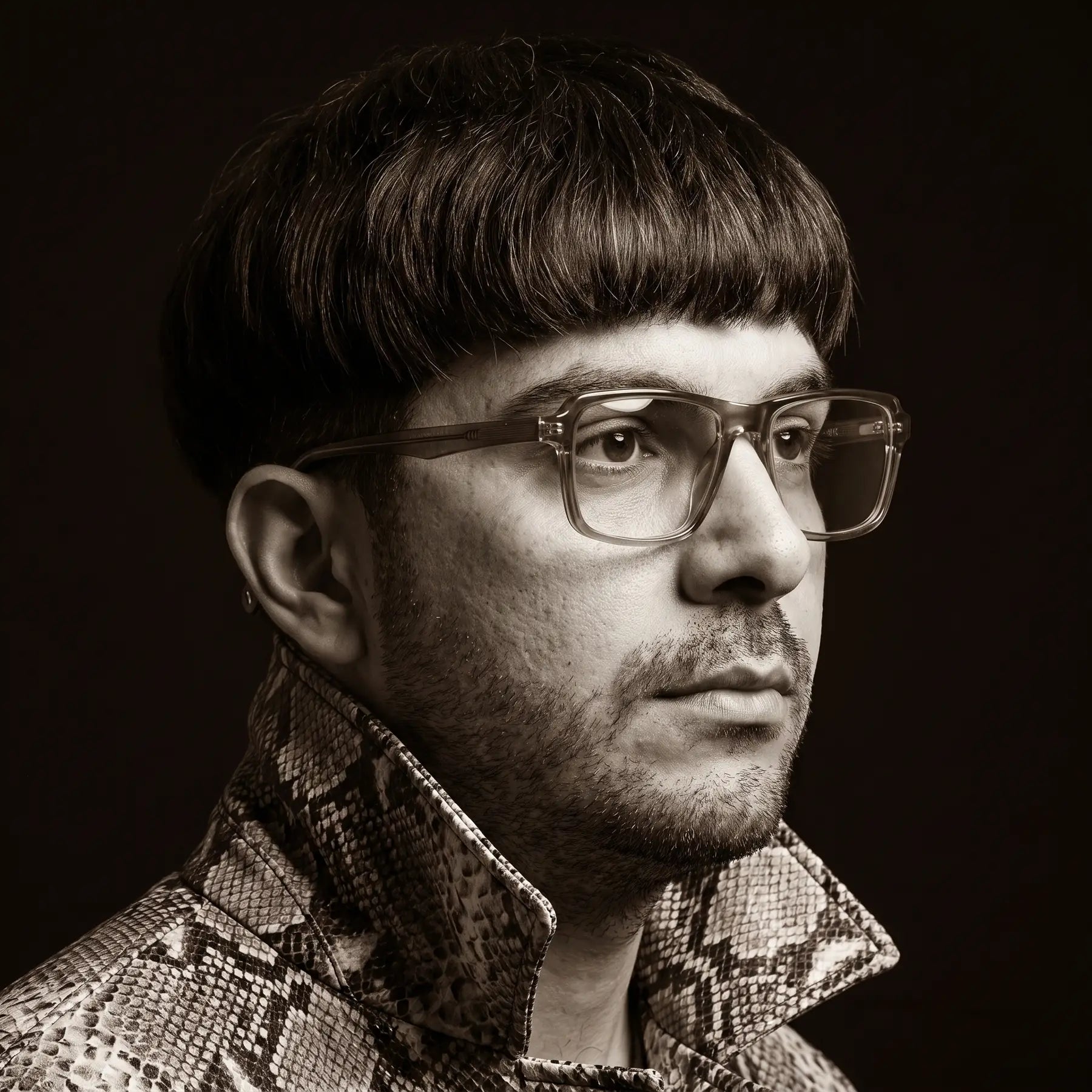 Anteojos Fiore 1038 en café, en modelo – retrato de campaña, monochrome studio portrait, red graphic accents