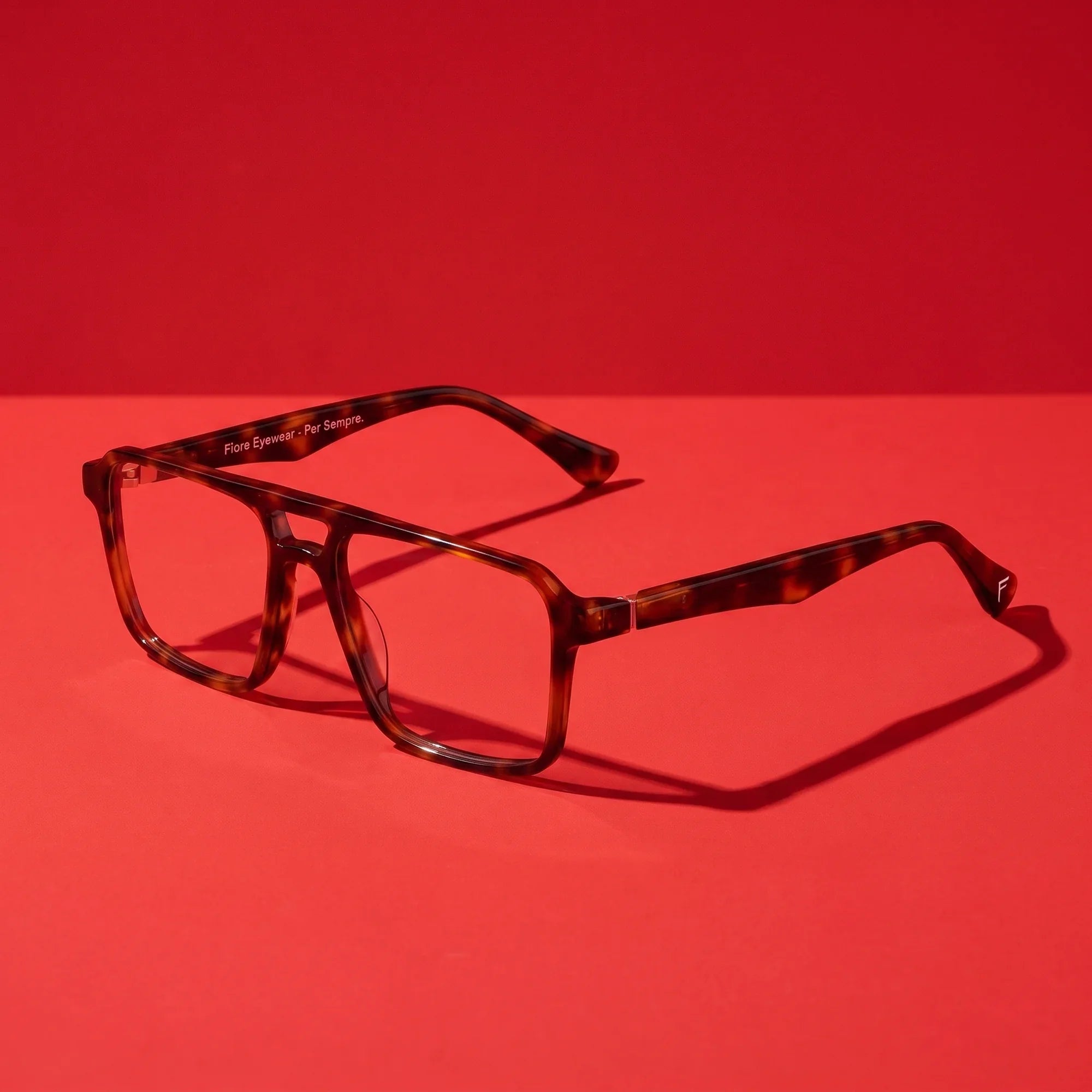 Anteojos Fiore 1039 en tortoiseshell – hero still life against a deep vivid red backdrop