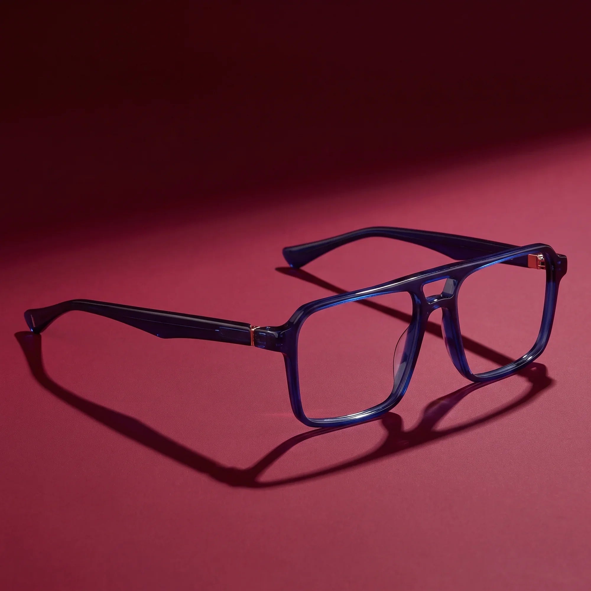 Anteojos Fiore 1039 en azul – editorial still life on a saturated burgundy set